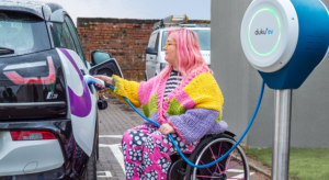 wheelchair user charges EV with cable management device